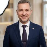 Профессиональный портрет Юрия Роста с уверенным и дружелюбным взглядом на нейтральном размытом фоне