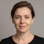 Профессиональный портрет Юрия Роста с уверенным и дружелюбным взглядом на нейтральном размытом фоне
